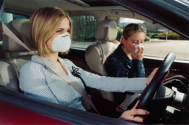 Two women sat in a car, both wearing face masks to protect themselves.