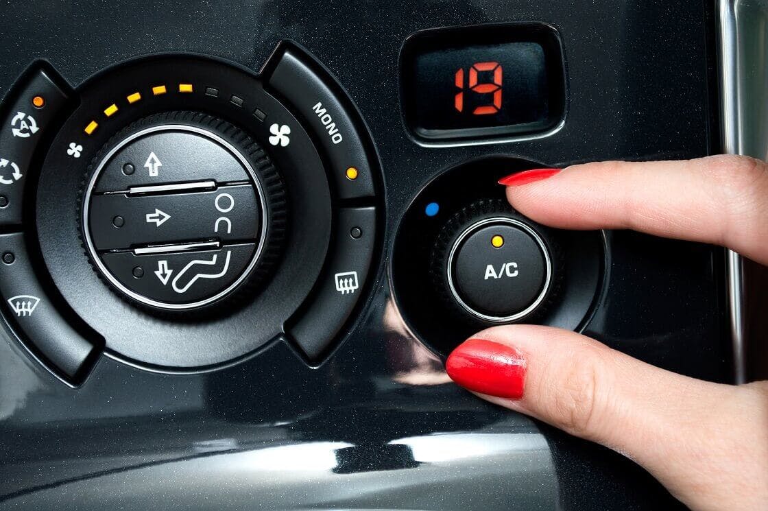 The article title over a woman's hand turning the Air-con control up in her car.