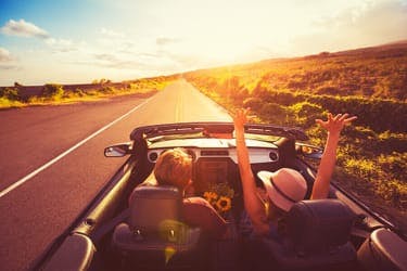 carefree drivers in convertible car on sunny day driving down scenic route