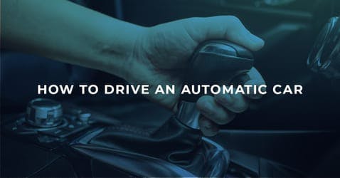 The article title over an automatic car gear stick, with the driver holding it in drive. 