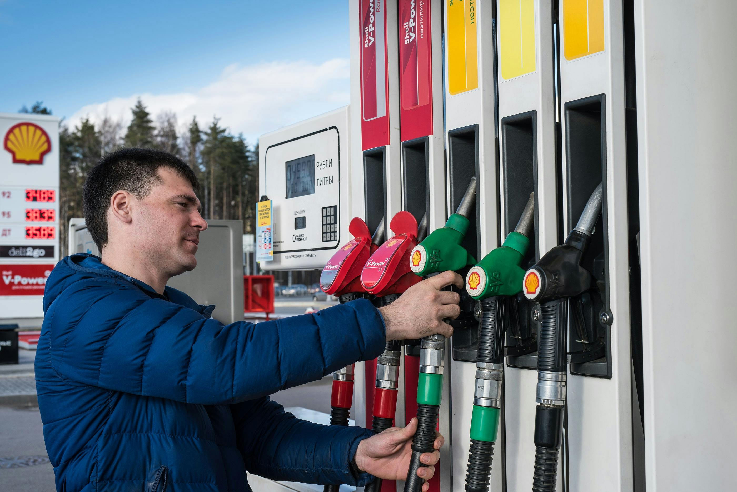 male driver choosing premium fuel pump at local petrol station to refuel car