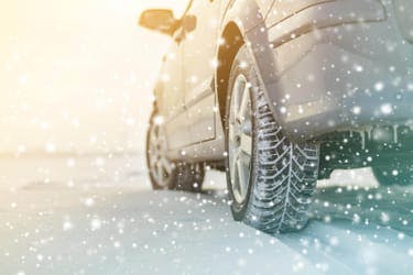 The article title over a car driving in winter, with snow-covered tyres.
