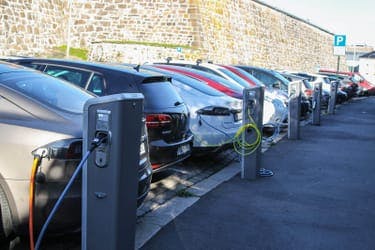 row of electric cars charging at public charging point, future of driving after 2030