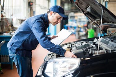 The article title over a mechanic checking under the bonnet of a vehicle during a car service.