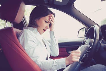 stressed female driver staring at invoice having been overcharged for MOT and servicing costs