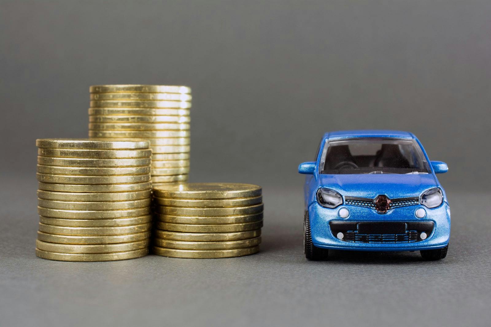 blue toy car next to piles of money, showing drivers' desire to save money due to cost of living