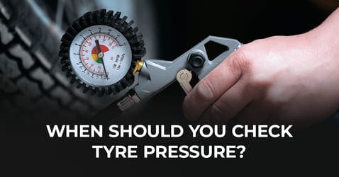 The article title over a hand checking tyre pressure with a gauge, with a black background.