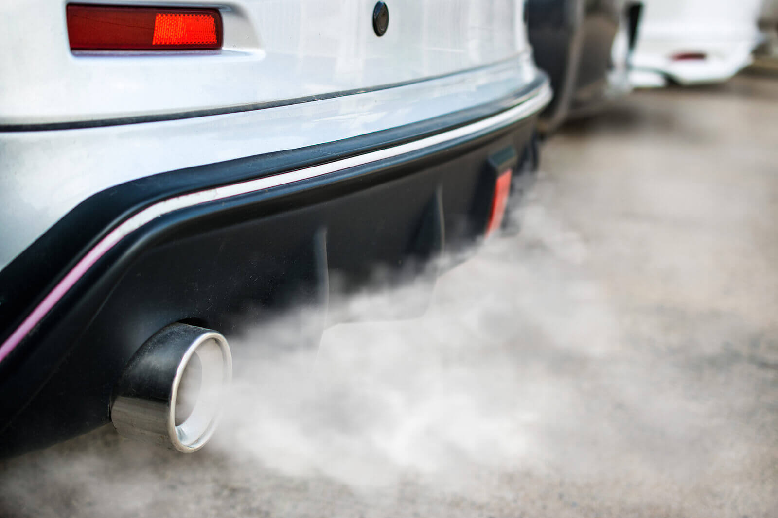 car exhaust smoking heavily, white smoke pouring out into atmosphere