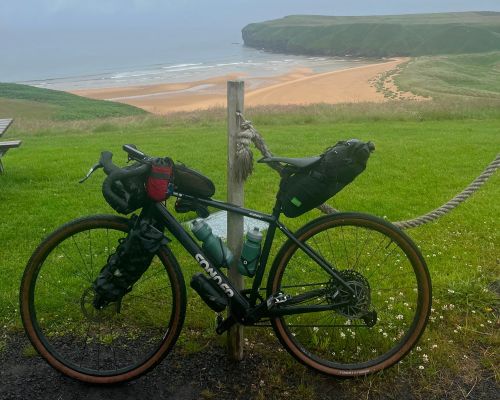 Ollie's bike parked overlooking a beautiful beach on the LEJOG journey